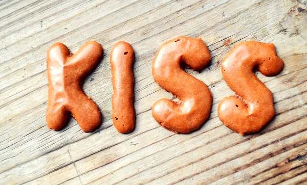 Λέξη φιλί από το αλφάβητο σοκολάτας μπισκότα στο ξύλινο τραπέζι — Φωτογραφία Αρχείου