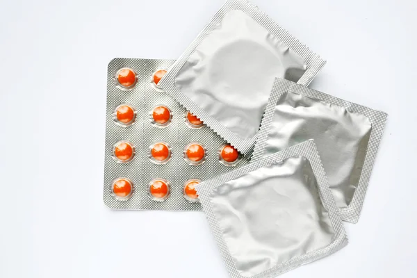 Drie condooms en geboortebeperking pillen geïsoleerd op wit — Stockfoto