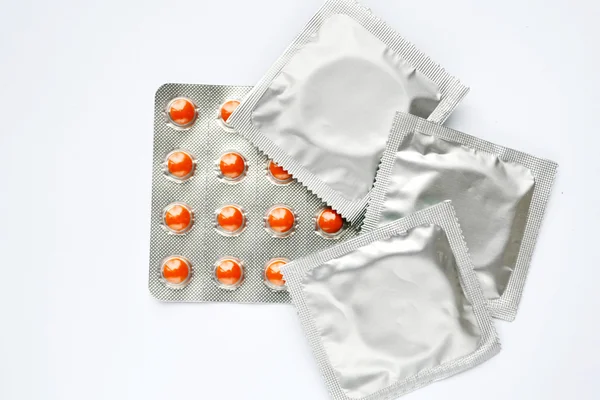 Three condoms and birth control pills isolated on white — Stock Photo, Image