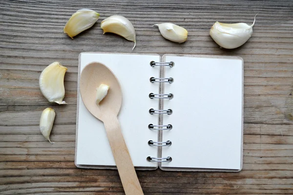 Un cuaderno en espiral retro vacío con cuchara de madera y dientes de ajo — Foto de Stock