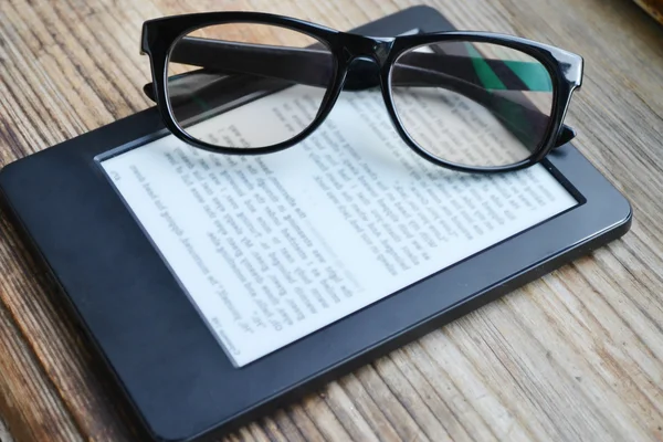 Black ereader with retro glasses on wooden table — Stock Photo, Image