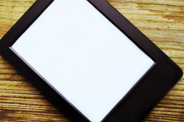 Black ereader with blank screen on wooden table