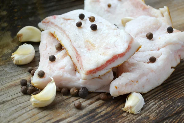 Witte varkensvlees vet genaamd salo met knoflook en peper op houten keukentafel — Stockfoto