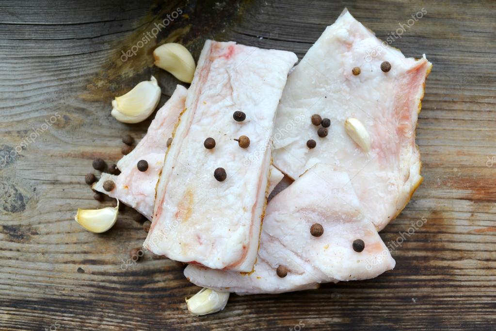 White pork fat called salo with garlic and pepper on wooden kitchen