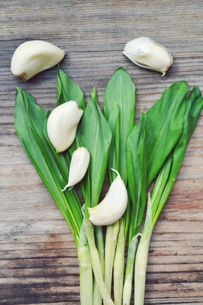 Wild leek with garlic cloves on wooden table — Stock Photo, Image