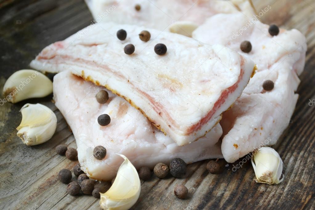 White pork fat called salo with garlic and pepper on wooden kitchen