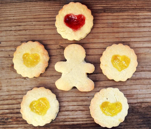 Homemade cookies in shape of man and with heart shaped jam on wooden table — Stock Photo, Image