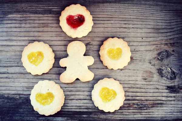 Homemade cookies in shape of man and with heart shaped jam on wooden table