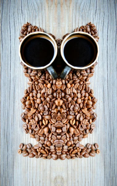 Banyak kopi panggang kacang dan cangkir kopi dalam bentuk burung hantu — Stok Foto
