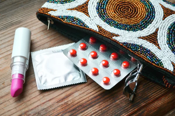 Couple de préservatifs et un ensemble de cosmétiques avec rouge à lèvres rose et friseur de cils — Photo