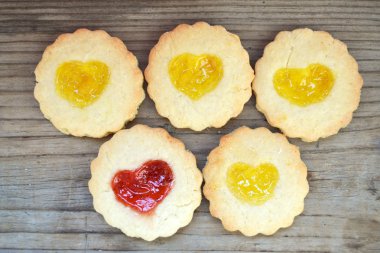 Ahşap masa üzerinde kalp şeklinde reçelli ev yapımı kurabiye