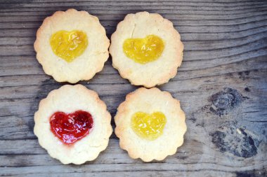 Ahşap masa üzerinde kalp şeklinde reçelli ev yapımı kurabiye