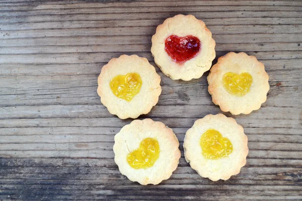 Ahşap masa üzerinde kalp şeklinde reçelli ev yapımı kurabiye