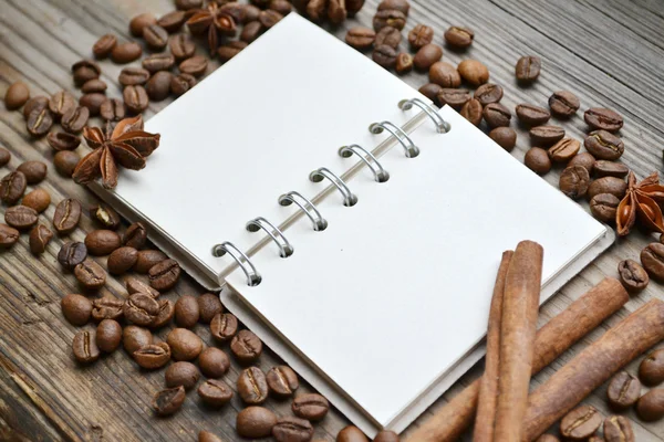 Un carnet spirale rétro vide avec beaucoup de grains de café torréfiés — Photo