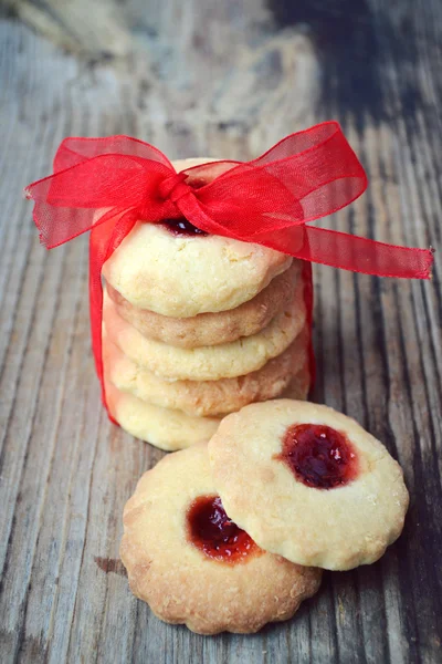 Galletas de mermelada caseras con lazo de cinta roja en mesa de madera — Foto de Stock