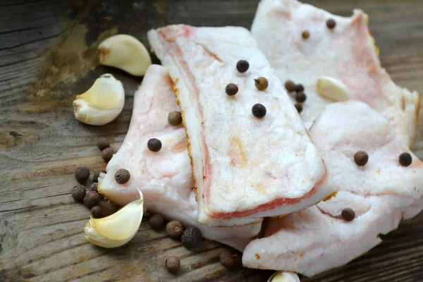 White pork fat called salo with garlic and pepper on wooden kitchen table