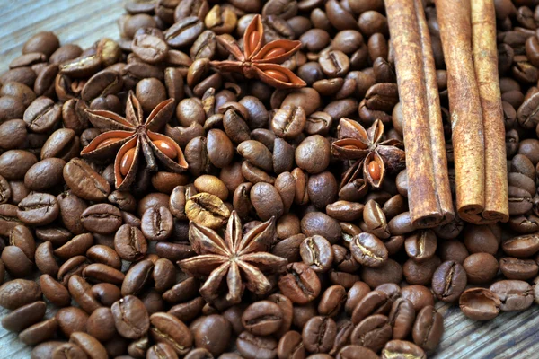 Spicy anise stars and cinnamon sticks on lots of roasted coffee beans — Stock Photo, Image