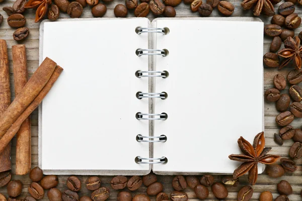 Un cuaderno en espiral retro vacío con muchos granos de café tostados — Foto de Stock