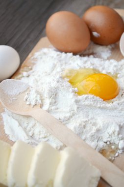 yumurta, tereyağı ve tahta kaşık yemek kartı üzerindeki beyaz un