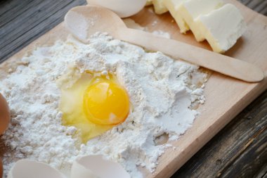 yumurta, tereyağı ve tahta kaşık yemek kartı üzerindeki beyaz un