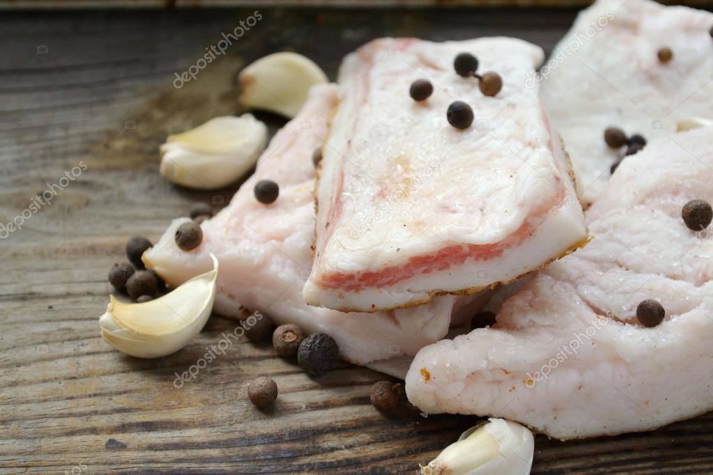 White pork lard called salo with garlic and pepper on wooden kitchen