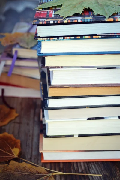 Högen av böcker med hösten lämnar på trä skrivbord — Stockfoto
