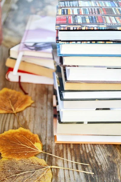 Pile of books with autumn leaves on wooden desk — Stock Photo, Image
