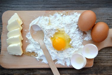 yumurta, tereyağı ve tahta kaşık yemek kartı üzerindeki beyaz un