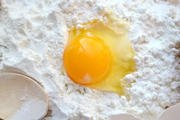 White flour with eggs, butter and wooden spoon on a cooking board — Stock Photo, Image