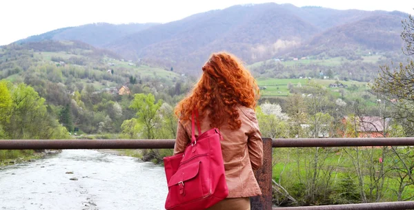Red haired woman looking at the mountains with her back to the camera