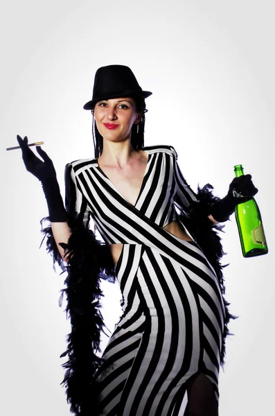 Joven hermosa morena con trenzas en un sombrero negro, plumas y vestido retro blanco y negro sosteniendo una botella de champán y un cigarrillo — Foto de Stock