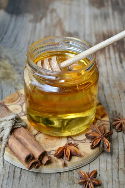 Golden honey with honeystick. cinnamon and anise stars on wooden table — Stock Photo, Image