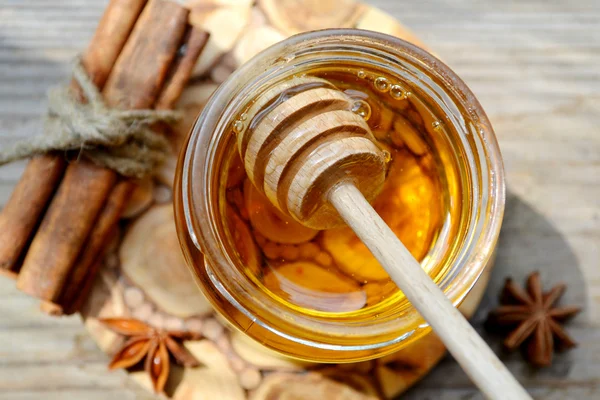 Golden honey with honeystick. cinnamon and anise stars on wooden table — Stock Photo, Image