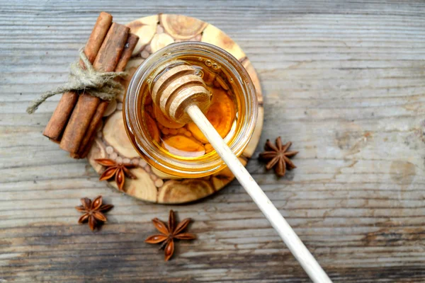 Golden honey with honeystick. cinnamon and anise stars on wooden table