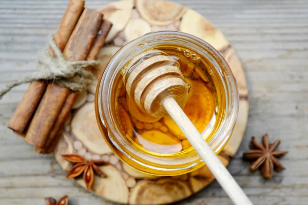 Golden honey with honeystick. cinnamon and anise stars on wooden table — Stock Photo, Image