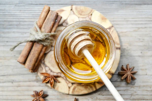 Golden honey with honeystick. cinnamon and anise stars on wooden table