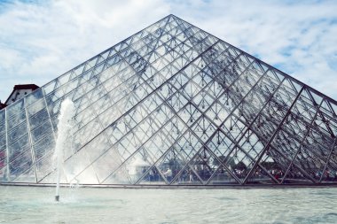 Paris, Fransa - 25 Mayıs, 2015: Ünlü Louvre Müzesi piramit yapılmış bardak mavi gökyüzü ve bulutlar yansımaları ile
