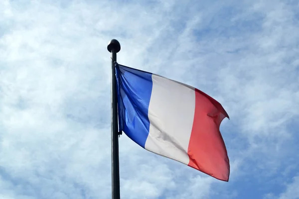 Integetett, ragyogó kék ég alatt Franciaország nemzeti zászlaja — Stock Fotó