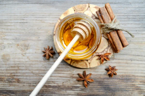 Golden honey with honeystick. cinnamon and anise stars on wooden table — Stock Photo, Image