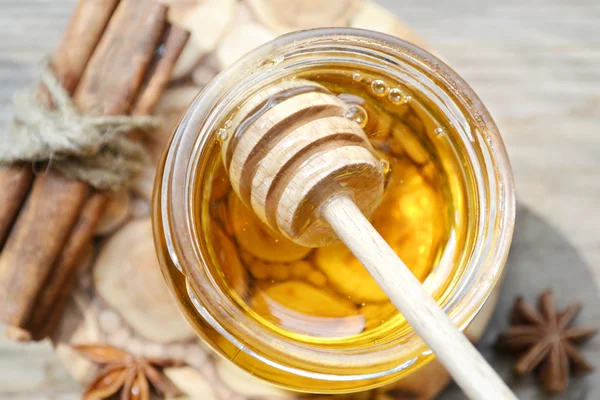 Golden honey with honeystick. cinnamon and anise stars on wooden table — Stock Photo, Image