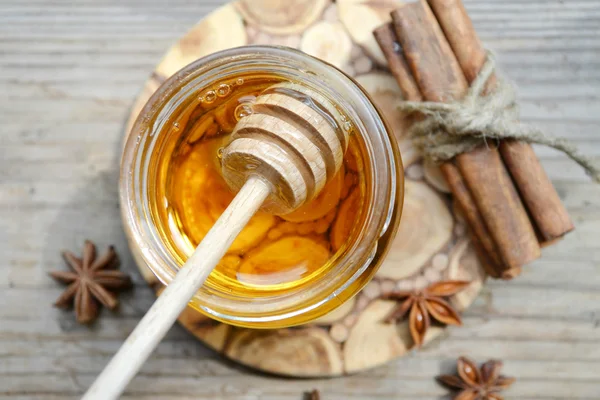 Golden honey with honeystick. cinnamon and anise stars on wooden table — Stock Photo, Image