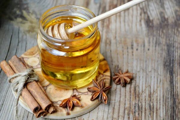 Golden honey with honeystick. cinnamon and anise stars on wooden table — Stock Photo, Image