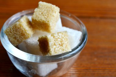 Ahşap masa üzerinde küçük bir kasede kesme beyaz ve kahverengi şeker