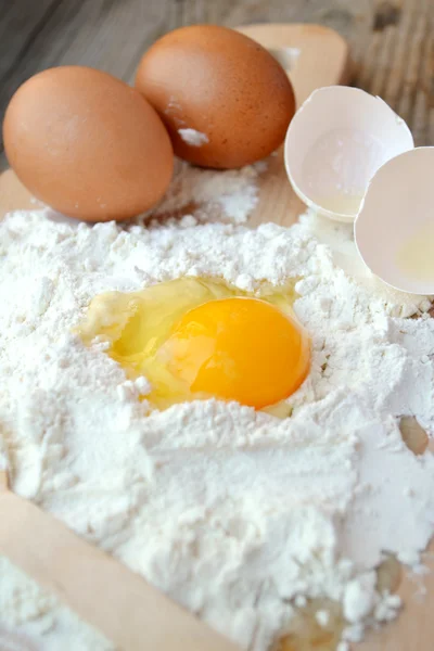 Farina bianca con uova, burro e cucchiaio di legno su un piano di cottura — Foto Stock