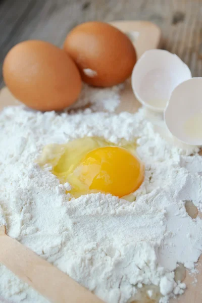 White flour with eggs, butter and wooden spoon on a cooking board — Stock Photo, Image