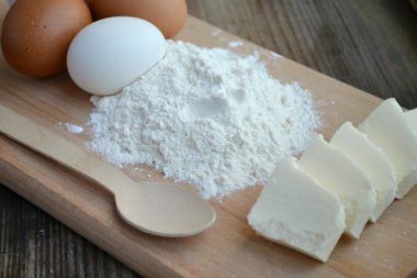 yumurta, tereyağı ve tahta kaşık yemek kartı üzerindeki beyaz un
