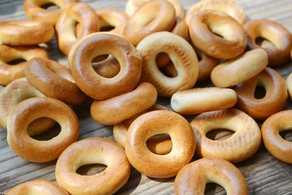 Beaucoup de petits bagels secs sur une table en bois — Photo