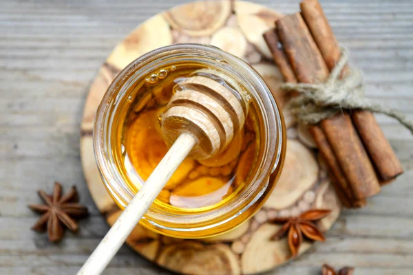 Golden honey with honeystick. cinnamon and anise stars on wooden table — Stock Photo, Image