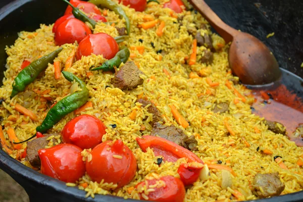 Olla grande con pilaf uzbeko con tomates y chiles verdes —  Fotos de Stock