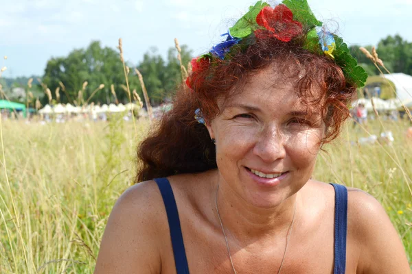 Happy beautiful redhead woman with flowers in her hair in her fourties smilling outdoors — Stock Photo, Image